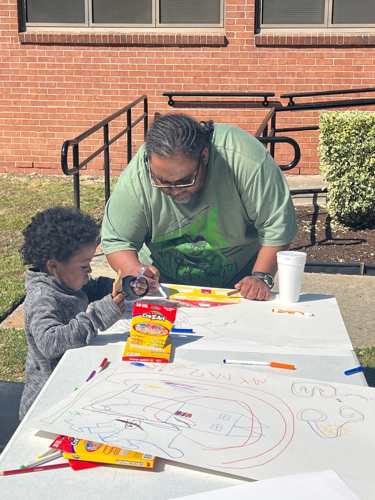 father and son coloring on table outside