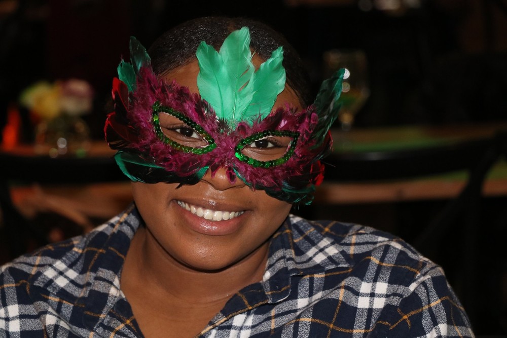 resident smiling with mardi gras mask on at banquet